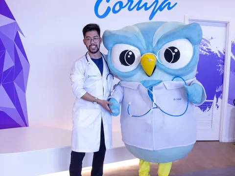 Aluno aprovado do Estratégia MED de jaleco, ao lado do Dr. Coruja