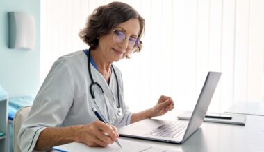 Imagem de uma médica estudando em frente ao computador com anotações a mesa que representa o artigo de fellowship em medicina