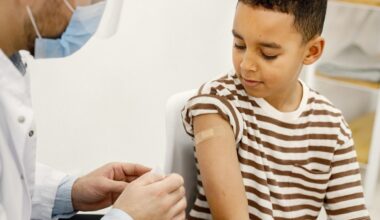 Um médico e uma criança com curativo no braço após tomar vacina